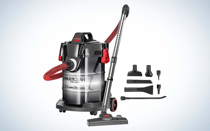 A gray vacuum cleaner body with a red tube and a gray attachment next to a group of attachments.