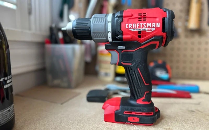 A red and gray Craftsman Power Drill in the foreground of a workspace.
