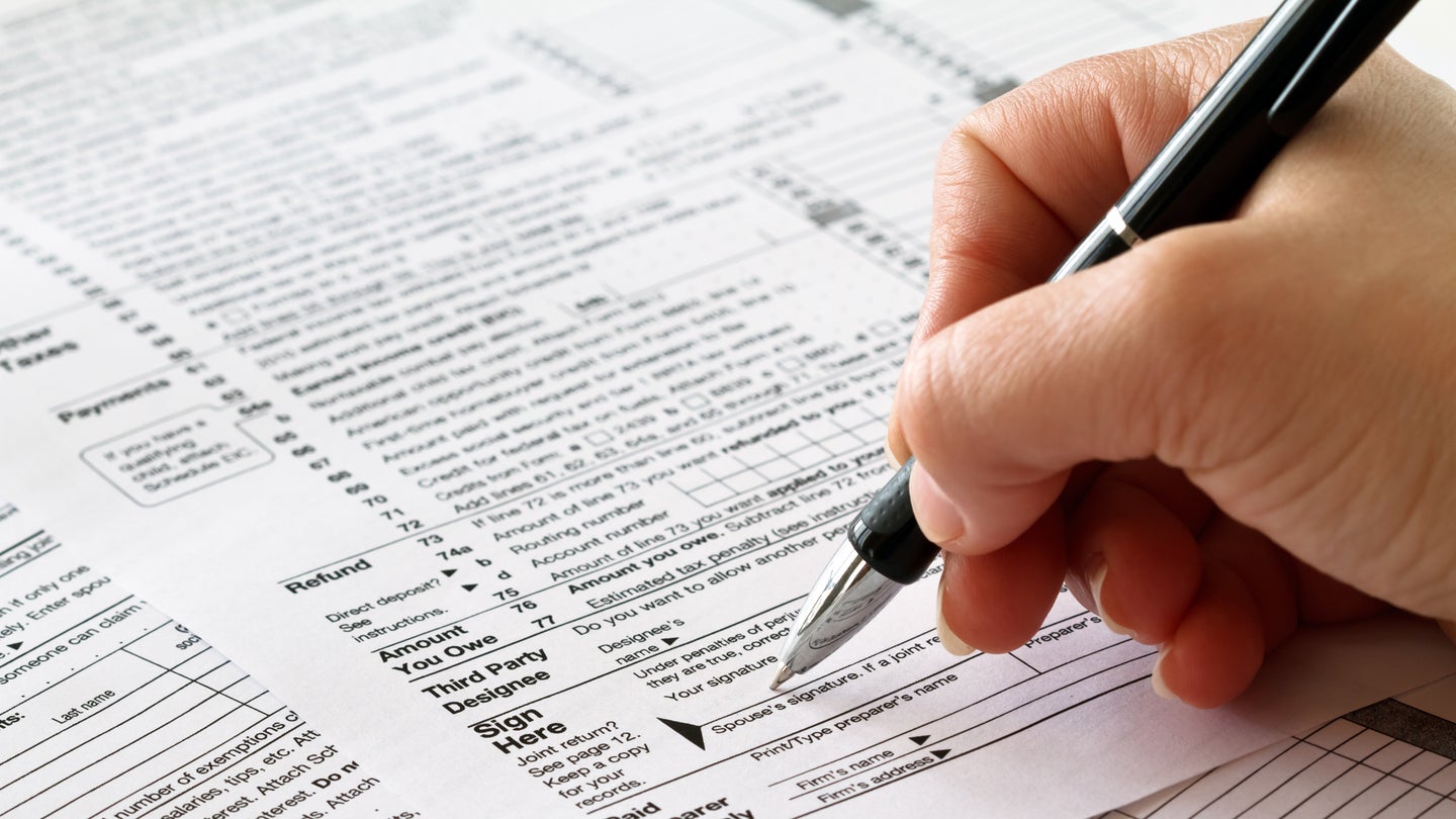 Close up of hand filling out paper tax filing form