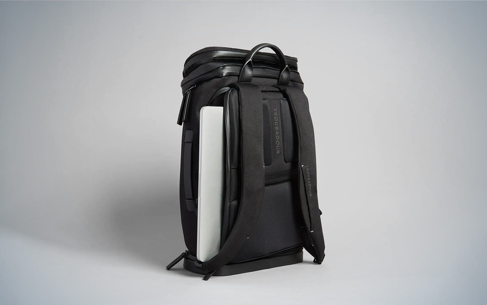 Black Troubadour Aero backpack with a silver laptop peeking out of the rear pocket